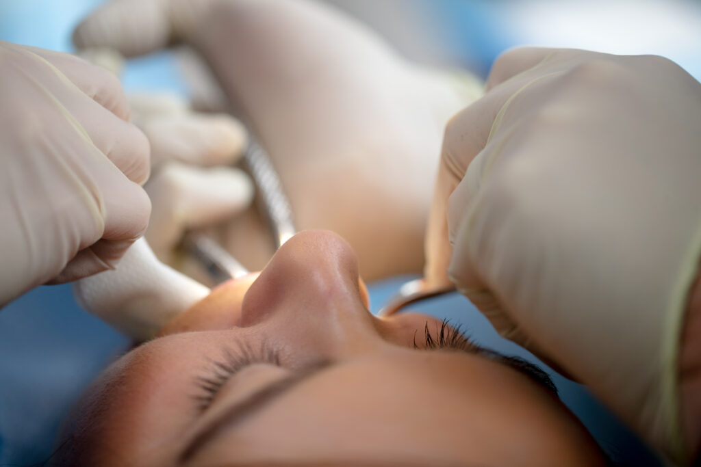 woman getting an oral surgery procedure such as a tooth extraction, dental implant, wisdom tooth removal, etc.